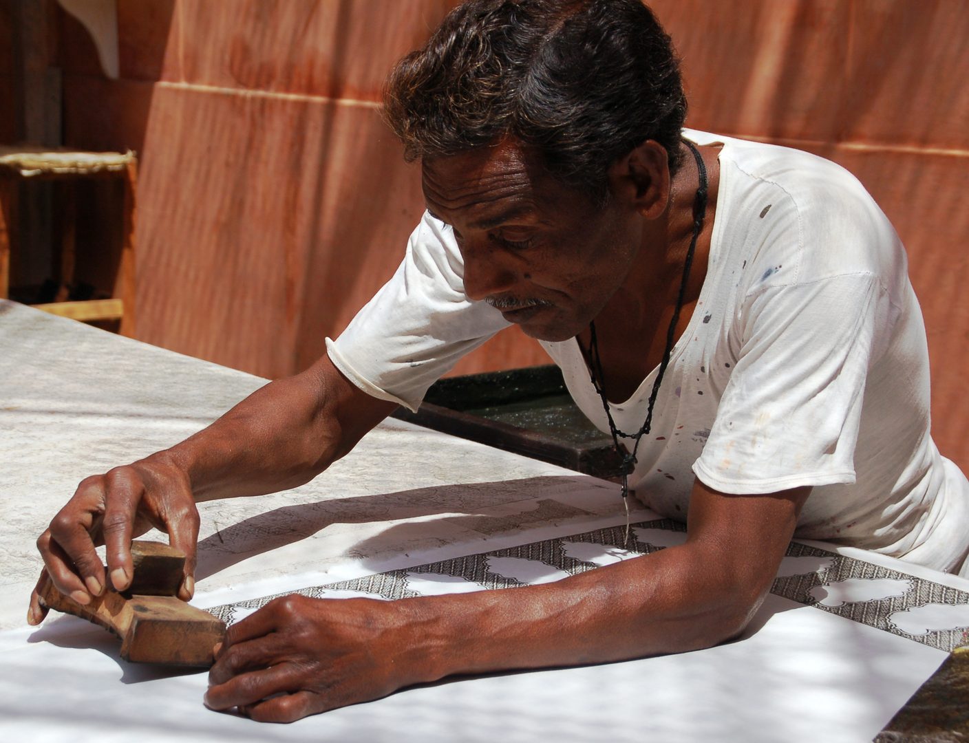 Craftsman hand-stamping vegetable dye patterns onto handspun cotton using carved teakwood blocks in Bagru