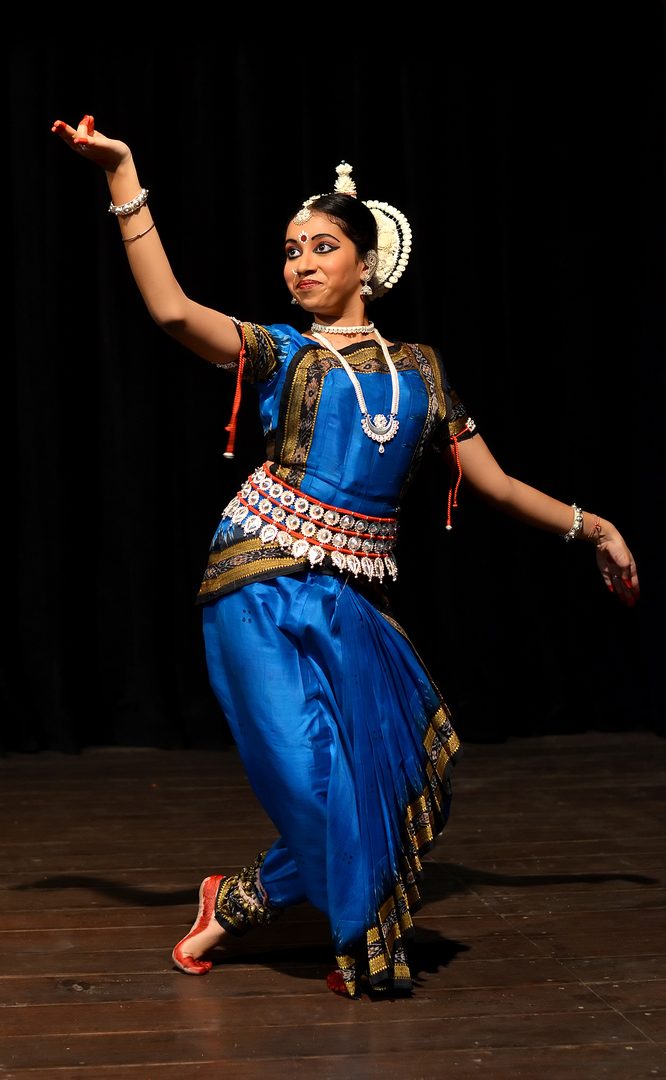 Classical Odissi dancer in silver filigree jewelry and traditional silk attire performing lyrical tribhangi stance
