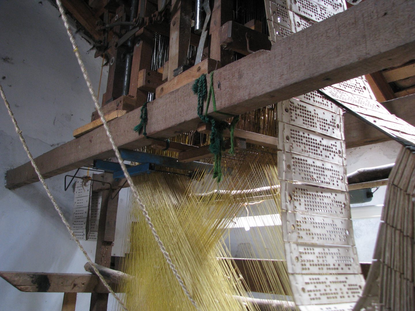 Generational master weaver threading pure gold zari into vibrant silk on a traditional Kanchipuram loom