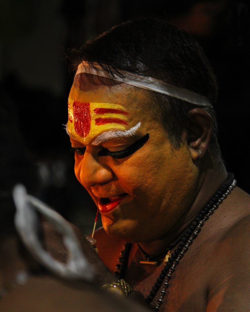 Master Kathakali performer with traditional paccha green facial makeup and ornate kiritam crown in Kerala