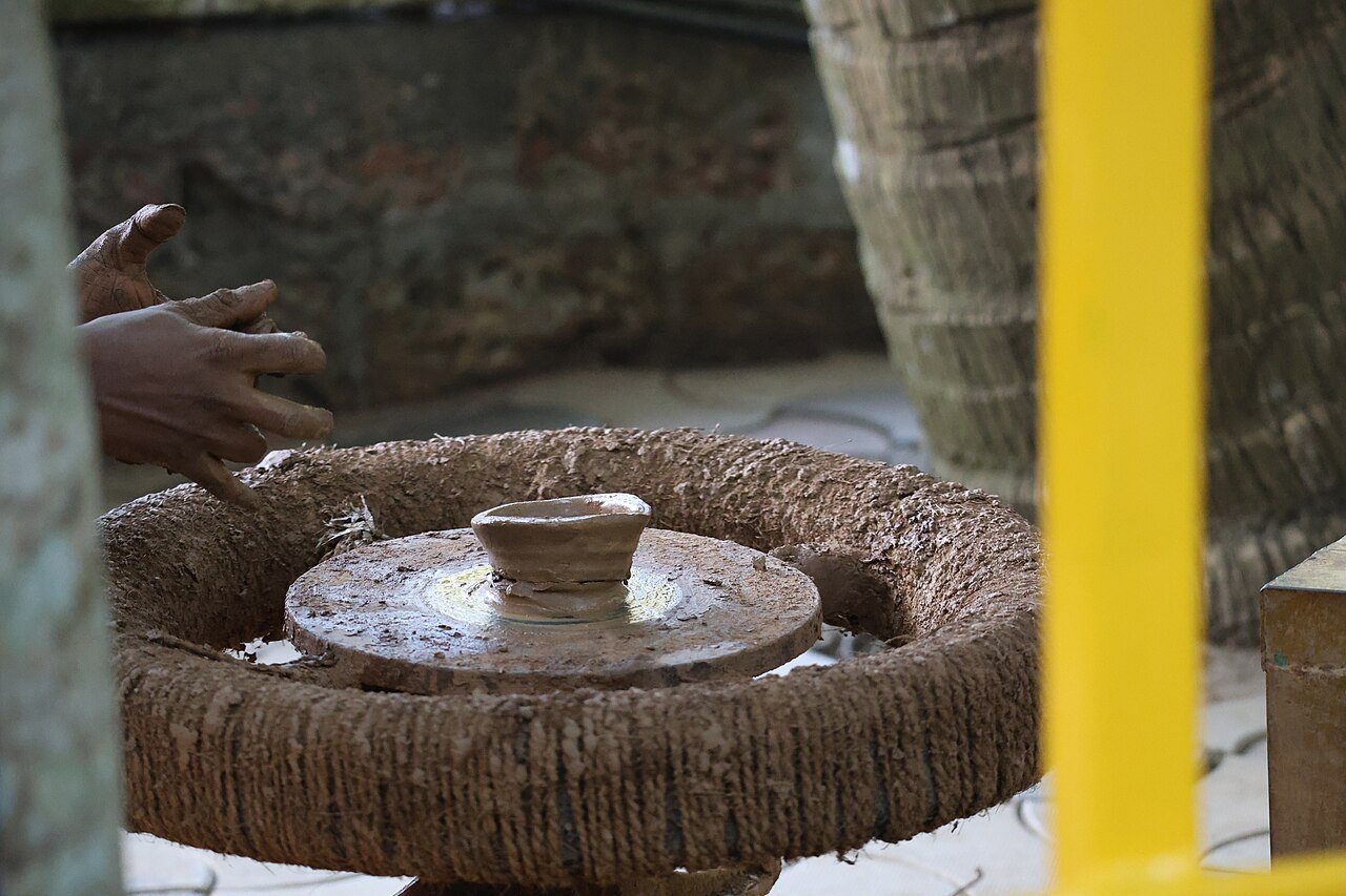 Master Indian potter shaping terracotta clay vessel on spinning wheel