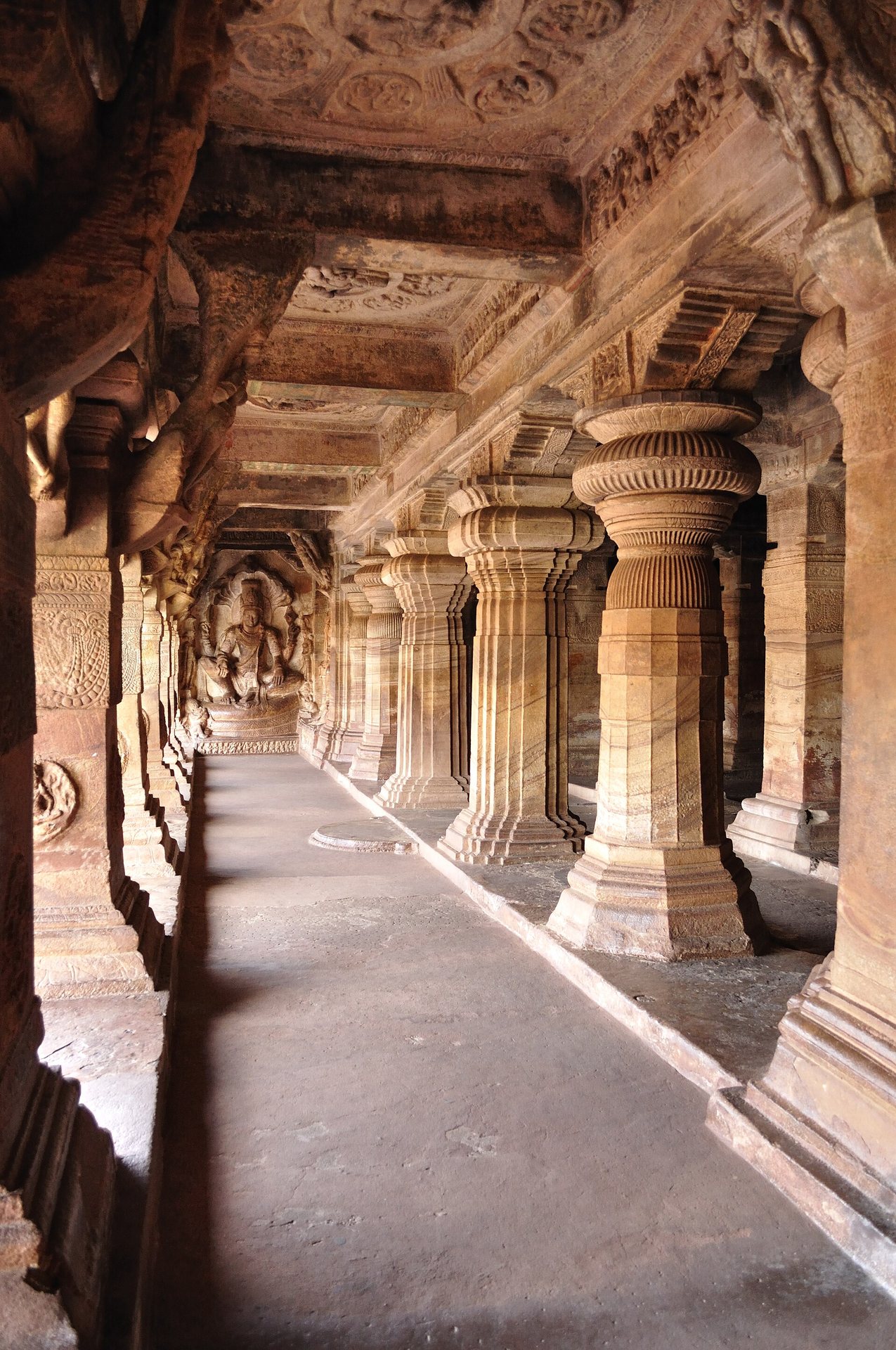 Ancient rock-cut cave temple entrance sculpted out of sheer sandstone cliffs in Badami
