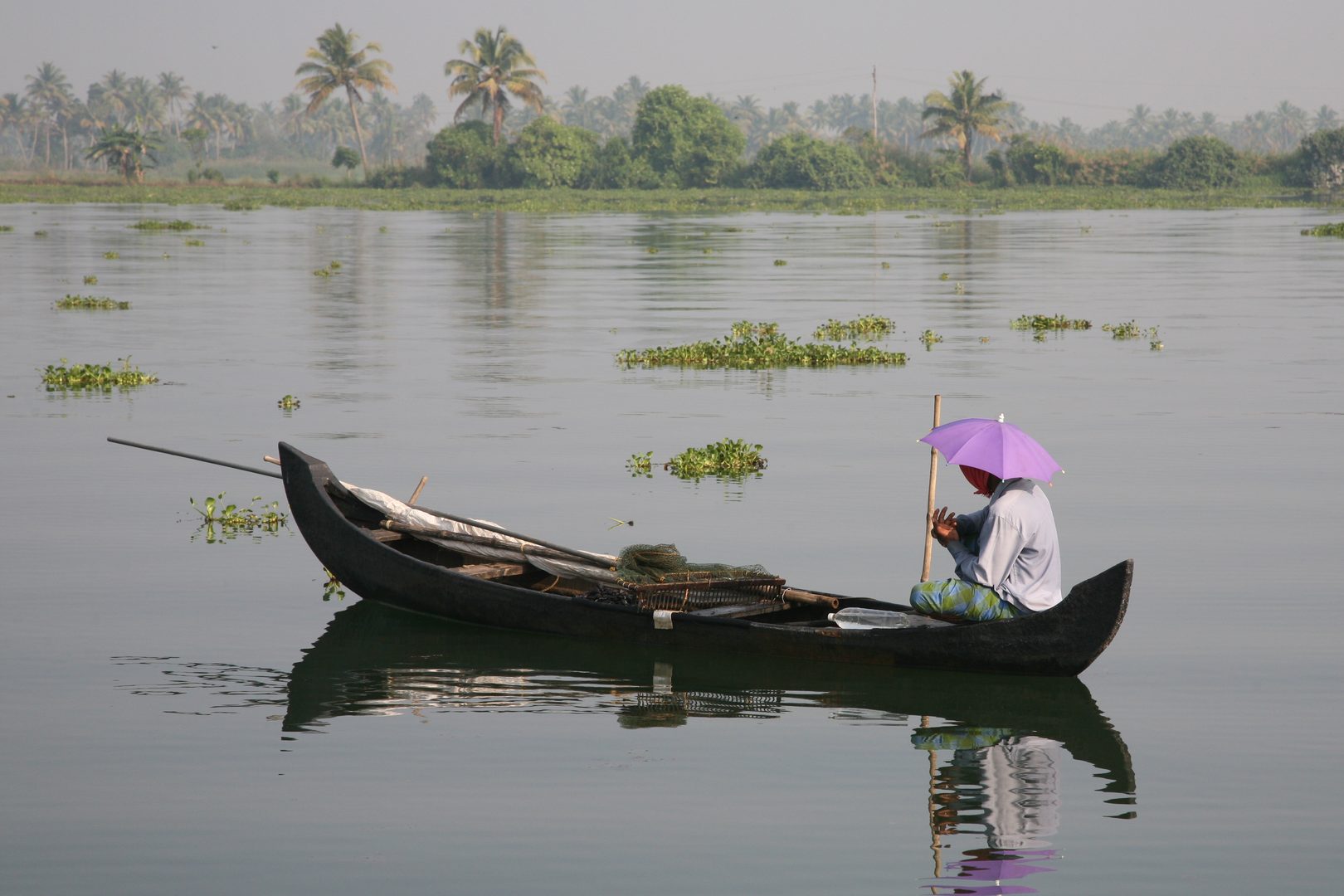 Traditional kettuvallam boat gliding through emerald waterways of Vembanad Lake in Kerala