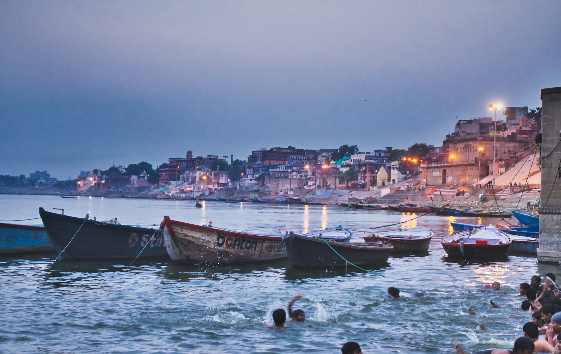 Dawn mist rising over traditional wooden rowing boats and ancient stone ghats of Varanasi