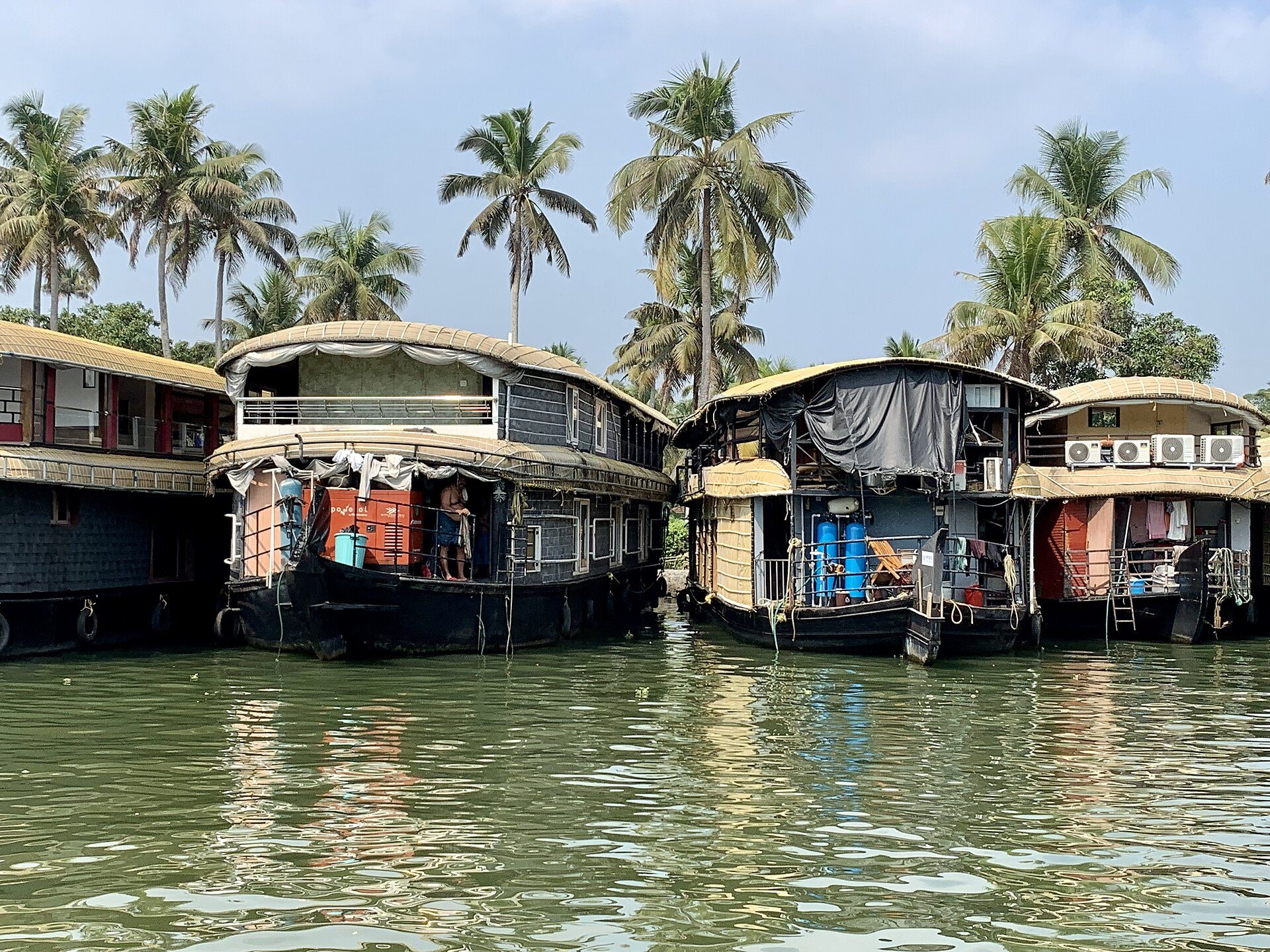 Tranquil emerald backwaters and traditional wooden houseboat gliding through palm-fringed lagoons in Kerala