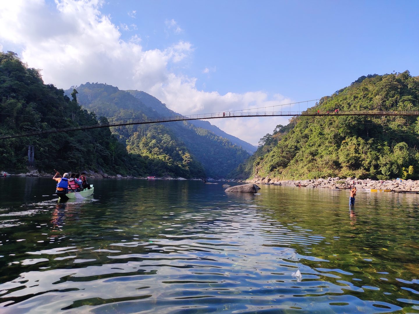 Wooden boat floating on the crystal-clear turquoise waters of the Umngot River in Dawki, Meghalaya