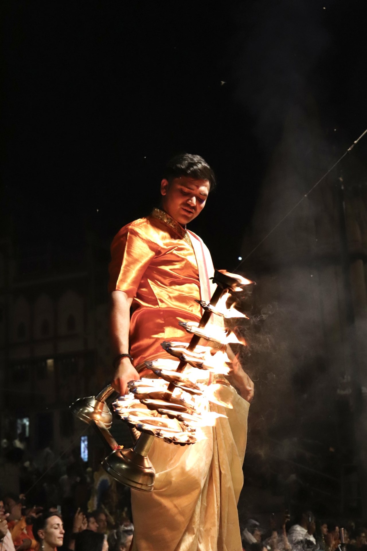 Priests performing sacred evening Ganga Aarti ritual with illuminated brass oil lamps along the Varanasi riverbank