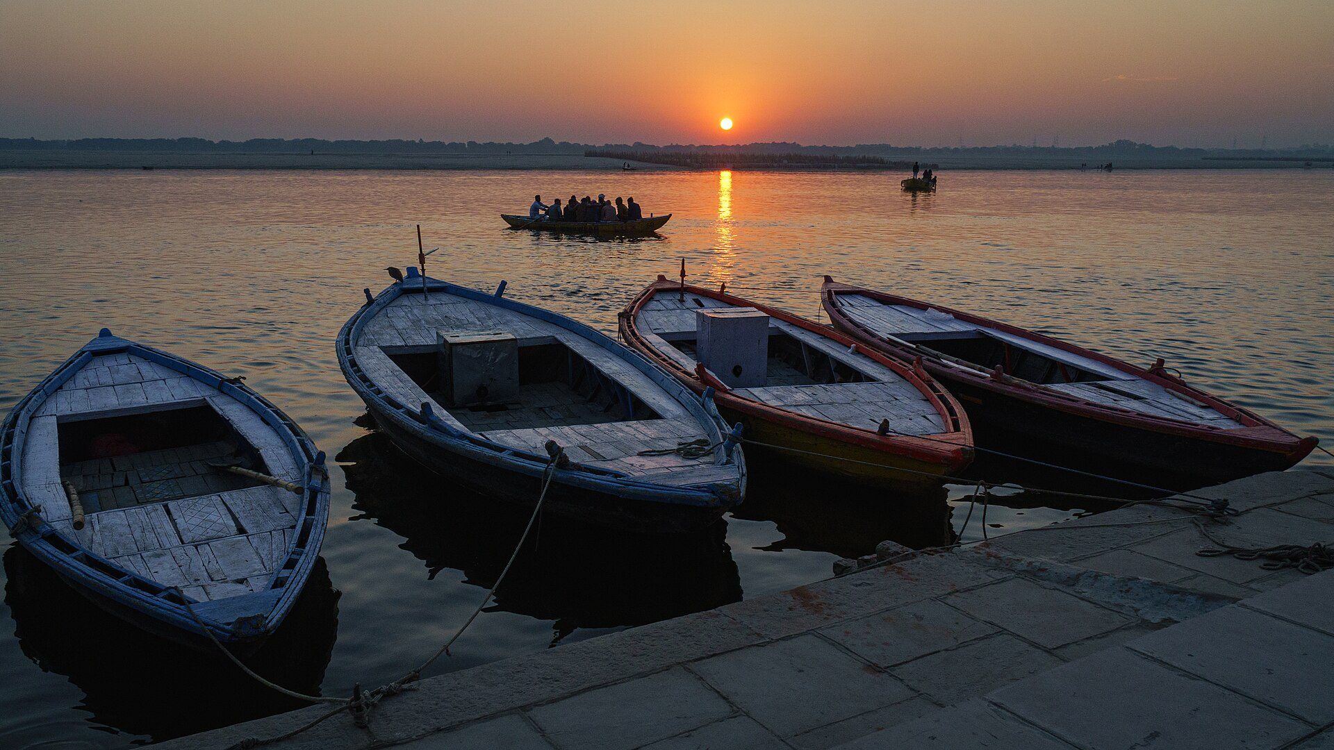 Dawn light breaking over the stone steps and historic wooden boats of Varanasi along the sacred Ganga