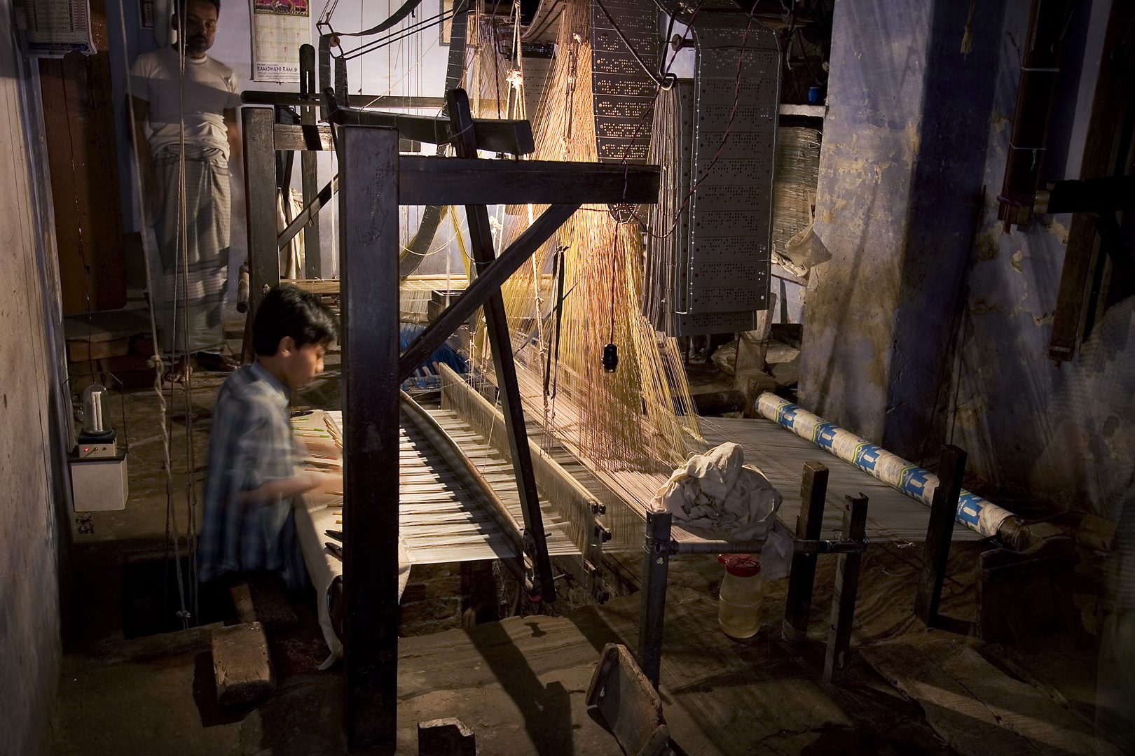 Master textile weaver guiding handloom craftsmanship in traditional Indian weaving colony
