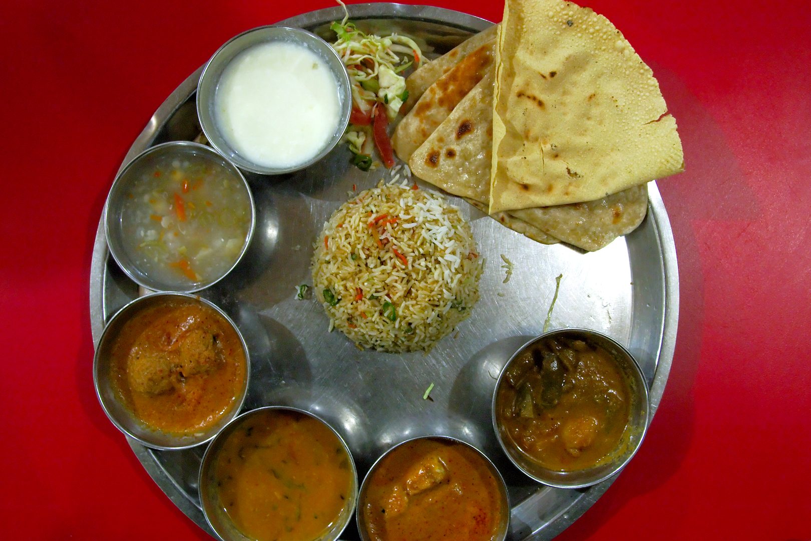Elaborate multi-course Indian royal dining spread with brass katoris and rich curries