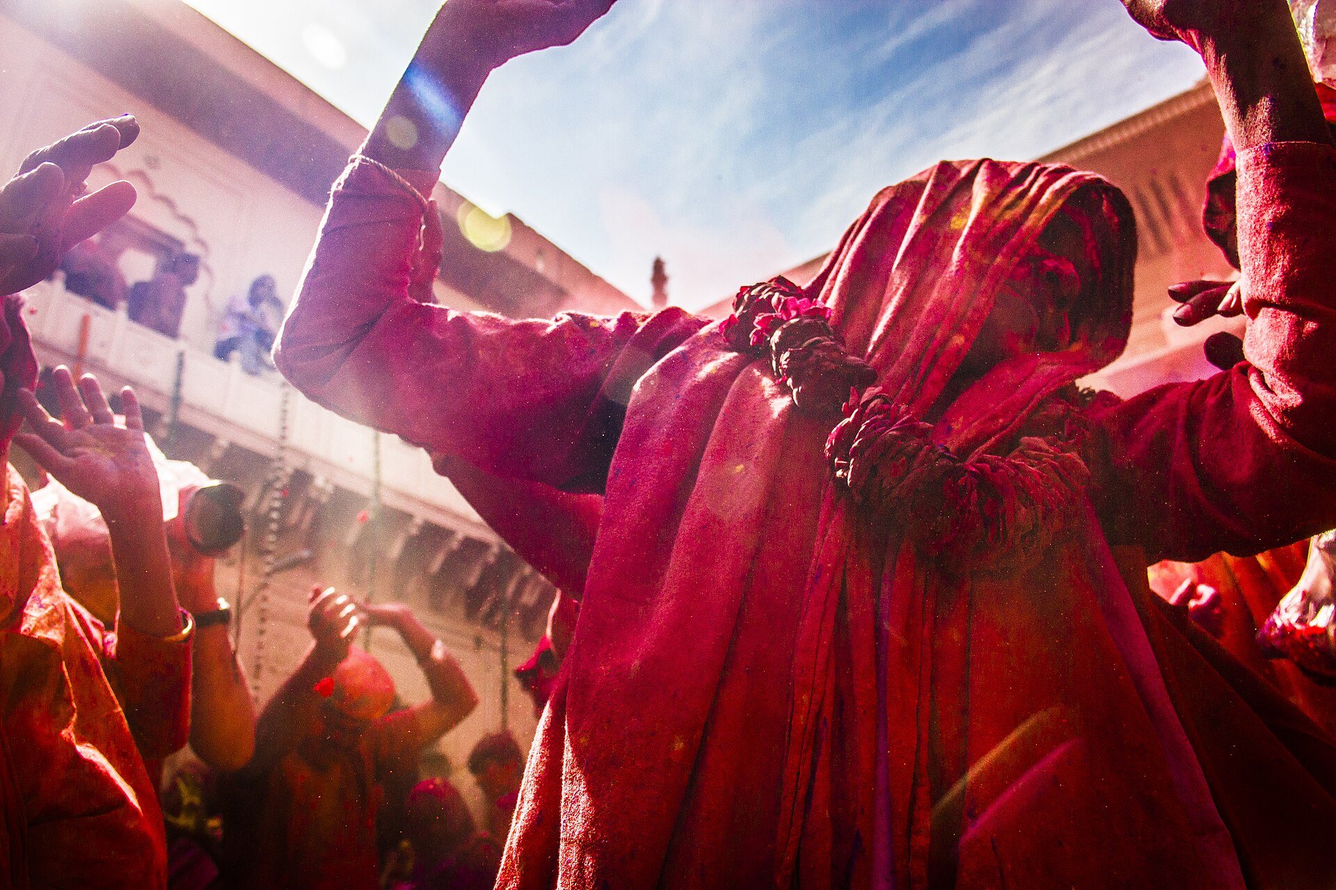 Joyous crowd celebrating Holi with vibrant colored gulal powder in Vrindavan