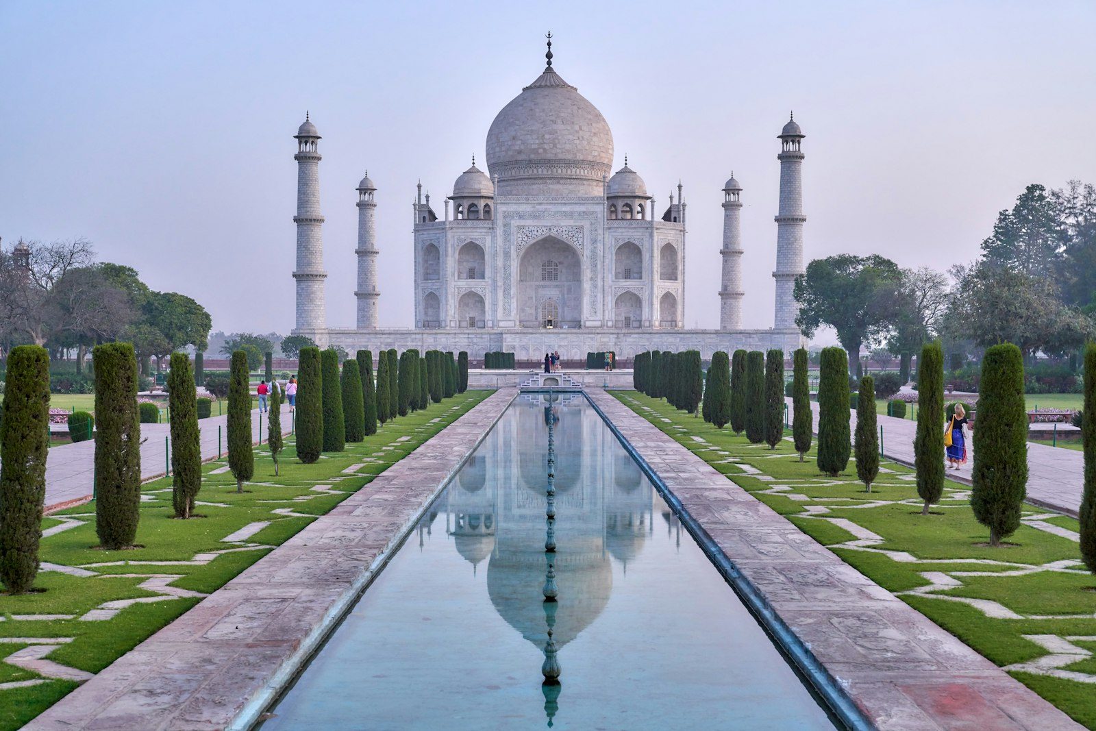 Red sandstone archway framing historic Mughal architectural courtyard