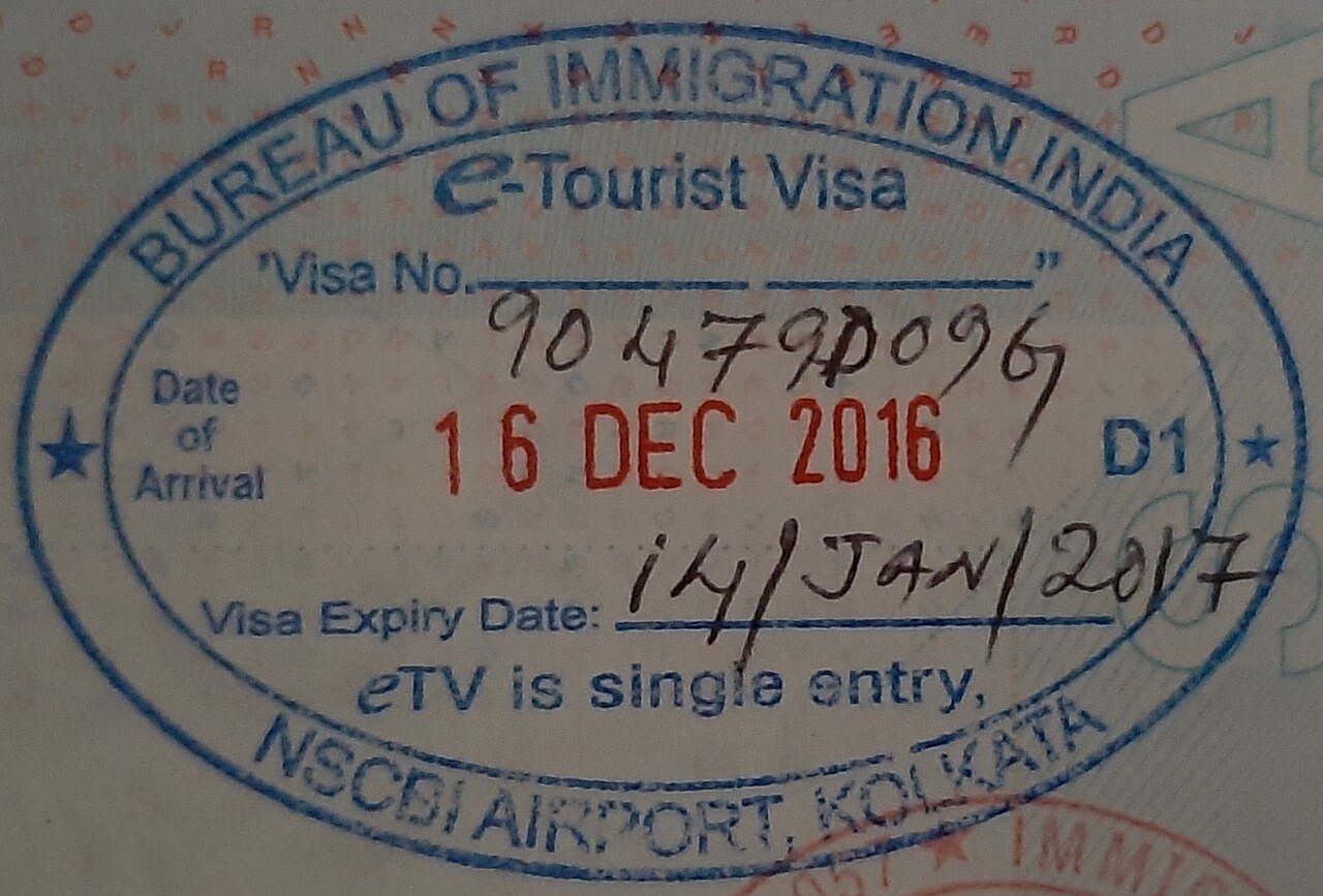 An international passport lying open next to Indian visa entry stamps, boarding passes, and official travel documents