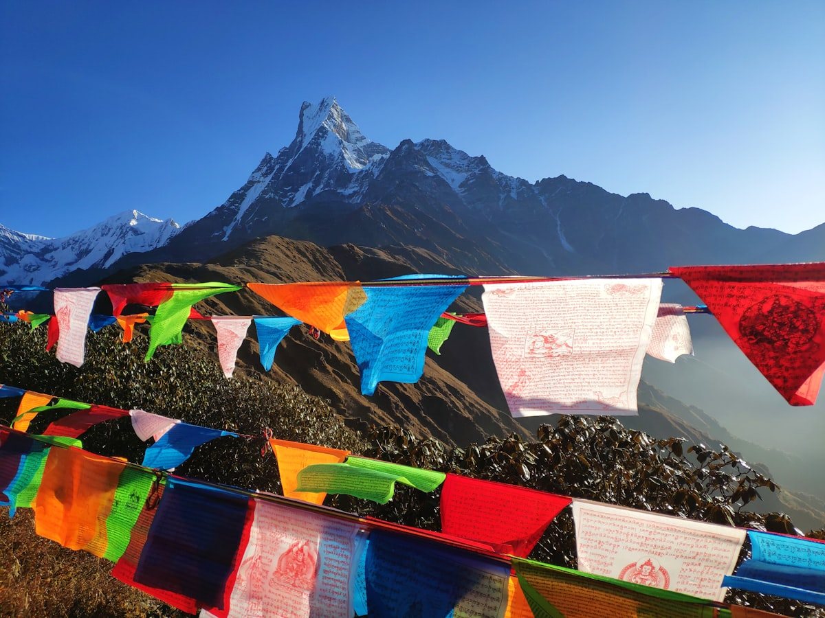 Five-color Buddhist prayer flags fluttering against soaring snow peaks in the Himalayas