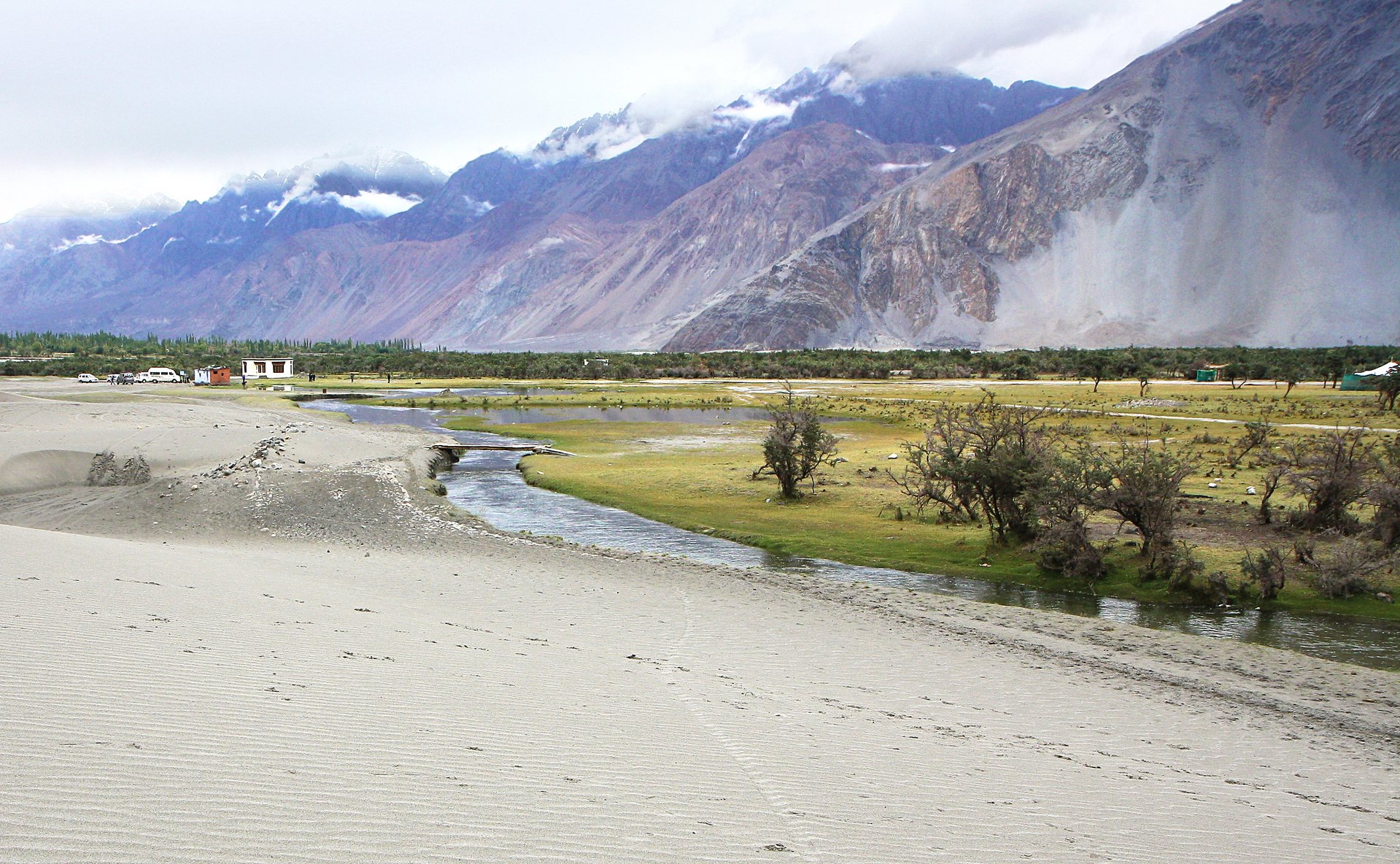 White sand dunes of Hunder in Nubra Valley framed by towering Himalayan mountains