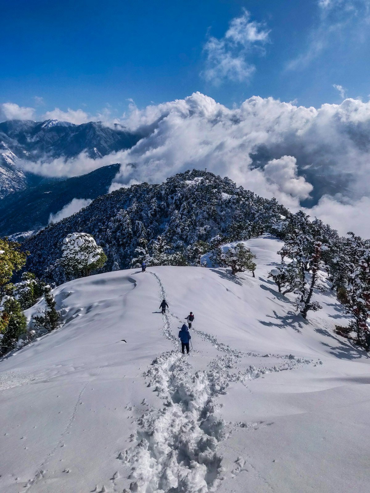 Winter expedition trekking across snowbound high Himalayan ridge above cloud inversions