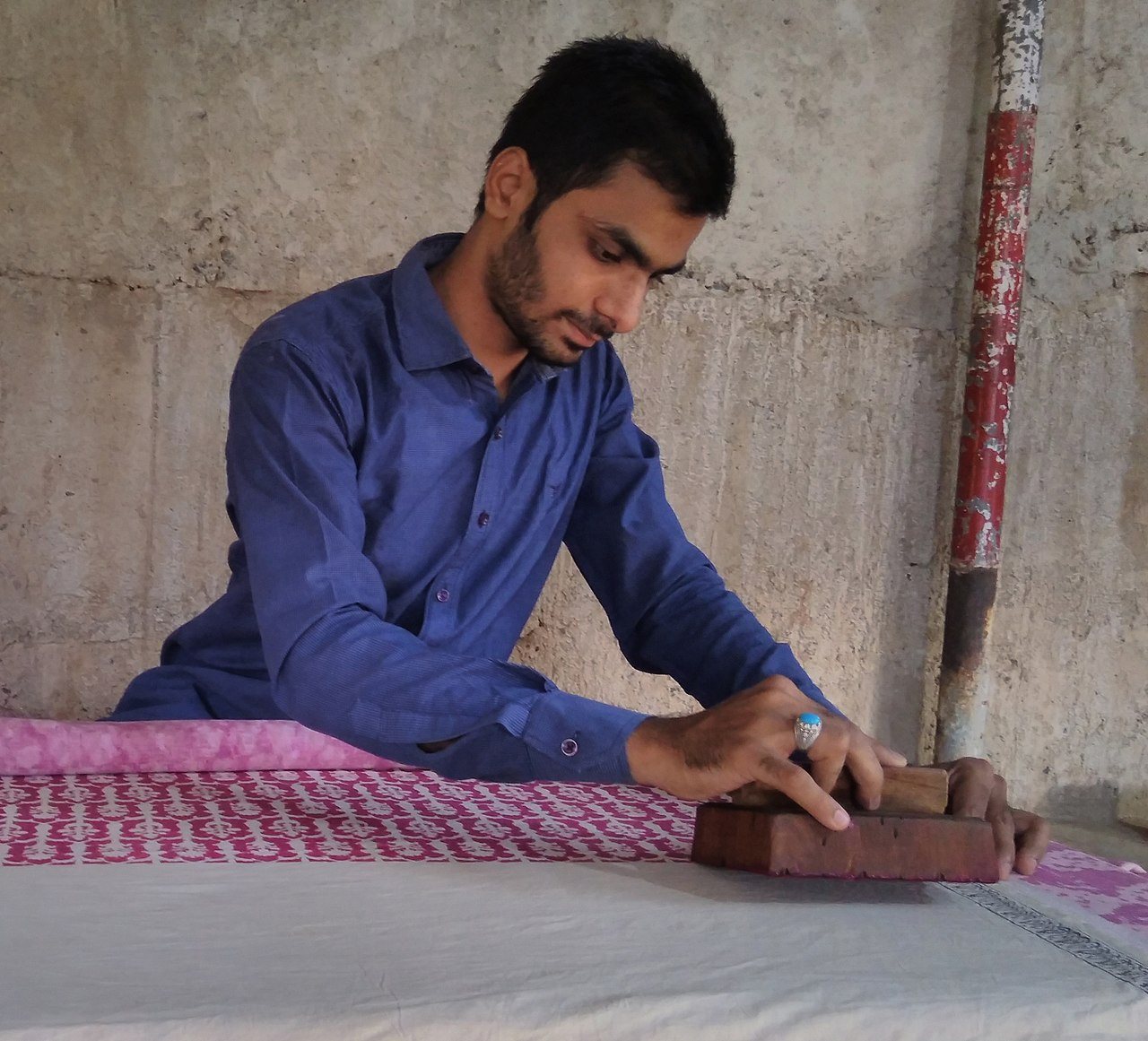 Artisan hand block-printing textile fabric with traditional carved wooden stamps and natural dyes