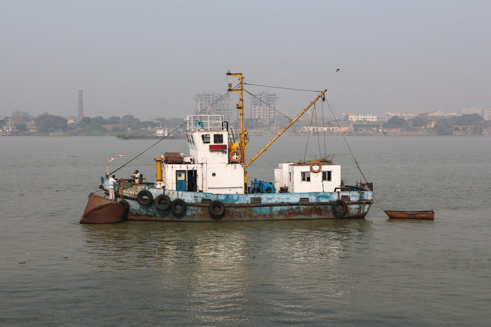 Serene wooden country boat floating on the wide tranquil waters of rural Bengal