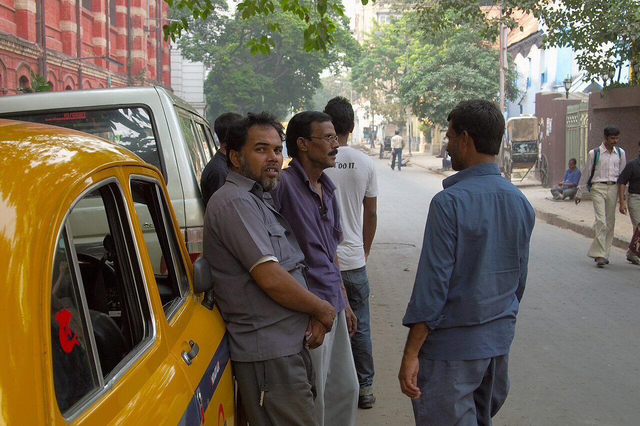 Classic yellow Ambassador taxi on bustling Kolkata heritage avenue