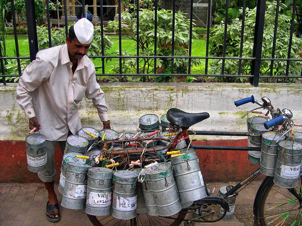 Mumbai dabbawalas balancing brass lunch carriers on bicycles through bustling city streets