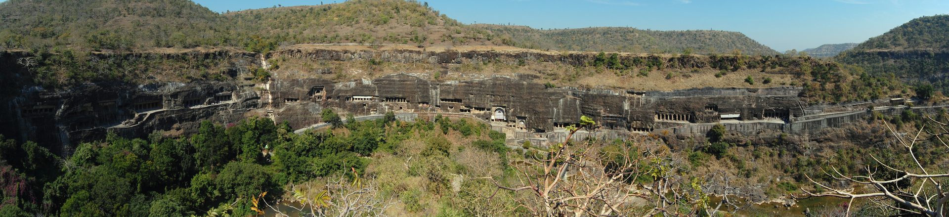 Traveler marveling at ancient rock-cut Buddhist facade and chaitya halls of Ajanta Caves